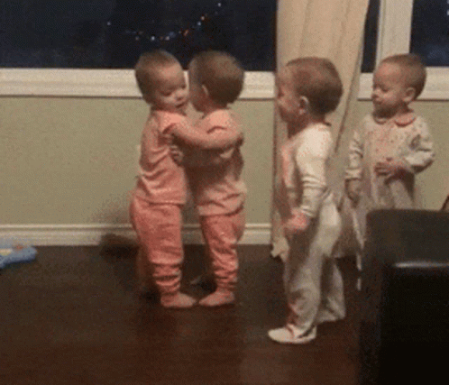 Three Babies In Pink Pajamas Are Hugging Each Other GIF