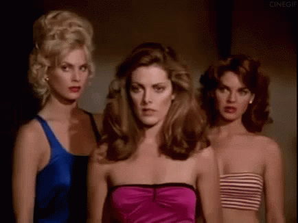 Three Beautiful Women Are Standing Next To Each Other In A Dark Room . GIF