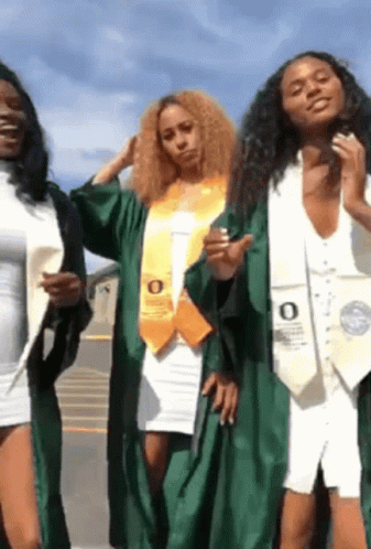 three female graduates are posing for a picture and one has the letter o on her sash .