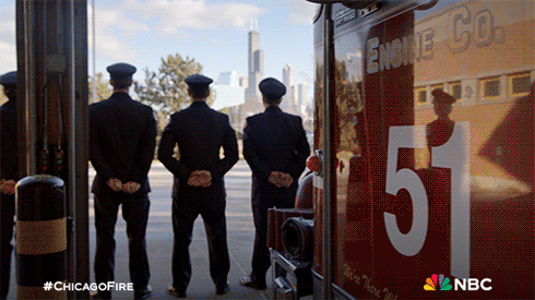 Three Firefighters Stand In Front Of A Chicago Fire Truck GIF