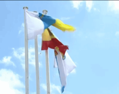Three Flags Are Flying In The Wind Against A Blue Sky With Clouds GIF