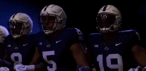 Three Football Players Standing In Dark Room GIF