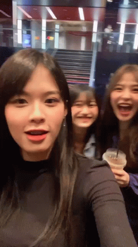 Three Girls Are Posing For A Picture And One Is Holding A Cup Of Coffee GIF