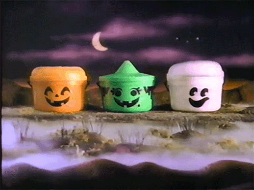 Three Halloween Buckets With Faces Painted On Them Are Sitting On A Rock GIF