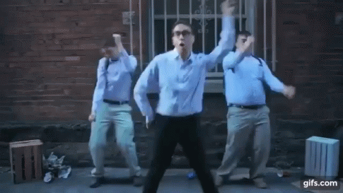 Three Men Are Dancing In Front Of A Brick Building . GIF