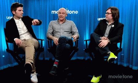 Three Men Are Sitting In Chairs In Front Of A Blue Curtain That Says Movietone GIF