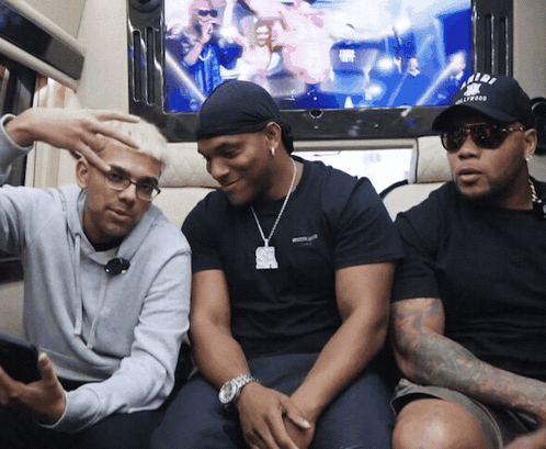 Three Men Are Sitting In Front Of A Tv And One Has A Hat That Says U.n.d.f. GIF