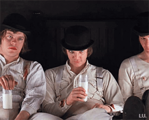 Three Men Are Sitting Next To Each Other And One Is Drinking Milk GIF