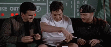 Three Men Are Sitting On A Couch In Front Of A Scoreboard And Laughing . GIF