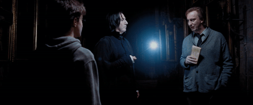 Three Men Are Standing In A Dark Room And One Of Them Is Holding A Letter GIF