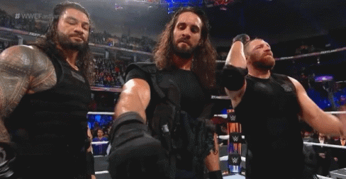 Three Men Are Standing In A Wrestling Ring Holding Hands . GIF