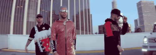 Three Men Are Standing In Front Of A Building And One Of Them Is Wearing A Jacket That Says Supreme GIF