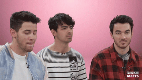 Three Men Are Standing In Front Of A Pink Background That Says Pop Blitz Meets On It GIF