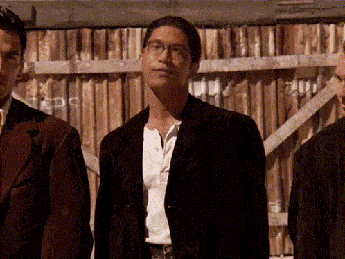 Three Men Are Standing In Front Of A Wooden Fence GIF