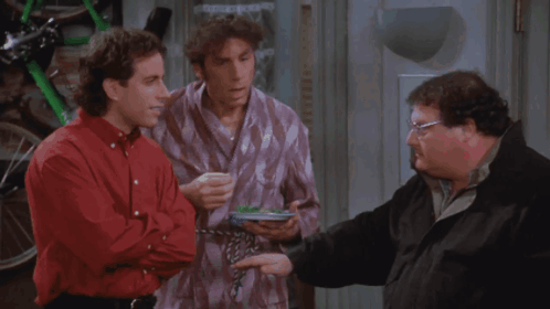 three men are standing next to each other and one has a plate of food