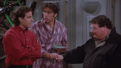 Three Men Are Standing Next To Each Other And One Of Them Is Holding A Remote Control GIF
