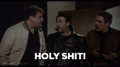 three men are standing next to each other in a room and one of them is holding a gun and saying holy shit .
