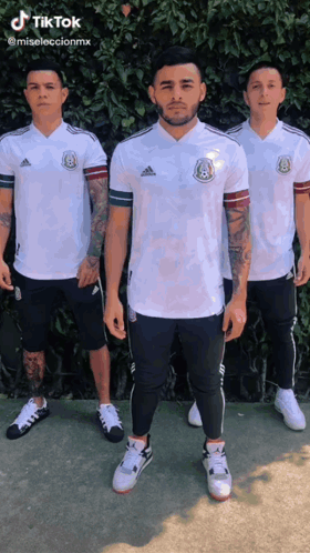 Three Men Are Standing Next To Each Other Wearing White Adidas Shirts And Shorts GIF