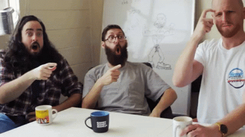 Three Men Around Table One Wearing the Bay Shirt