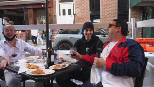 Three Men at Table with Food and Wine