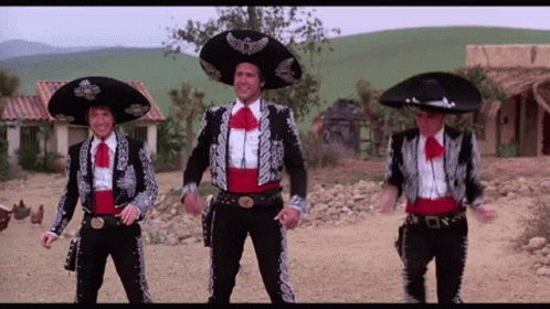 Three Men Dressed In Mariachi Outfits Are Dancing In A Dirt Field GIF
