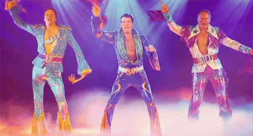 Three Men In Colorful Costumes Are Dancing On A Stage In Front Of A Crowd . GIF