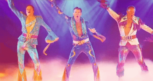 Three Men In Colorful Costumes Are Dancing On A Stage In Front Of A Purple Background . GIF