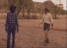Three Men In Cowboy Hats Are Standing In A Field . GIF