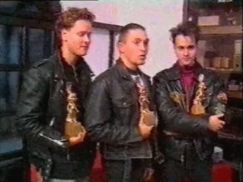 Three Men in Leather Jackets Holding Trophies