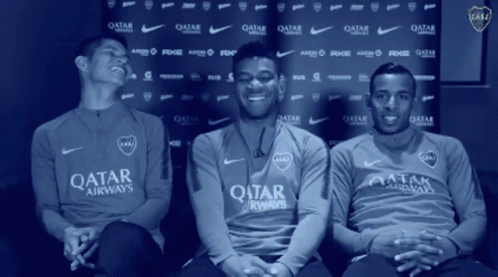 Three Men in Qatar Airways Shirts Sitting in Front of Blue Backdrop