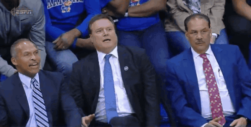 Three Men In Suits And Ties Are Sitting In The Stands At A Basketball Game GIF