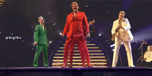 three men in suits are standing on a stage .