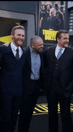 Three Men Posing In Front Of Thor's Boys Poster GIF