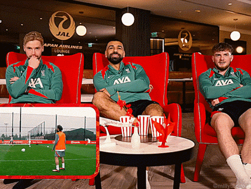 Three Men Sit In Red Chairs In Front Of A Japan Airlines Lounge Sign GIF