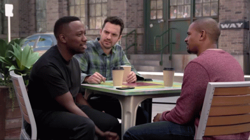 Three Men Sitting at Table in Front of Wave Sign