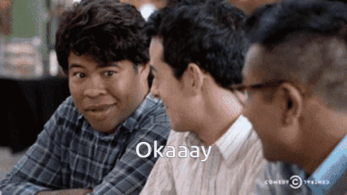 Three Men Sitting at Table One Saying Okay