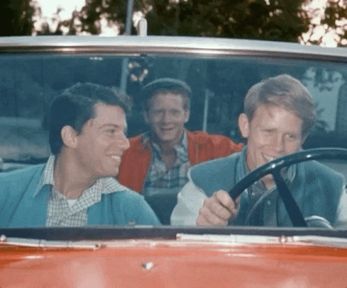 Three Men Smiling in Red Car
