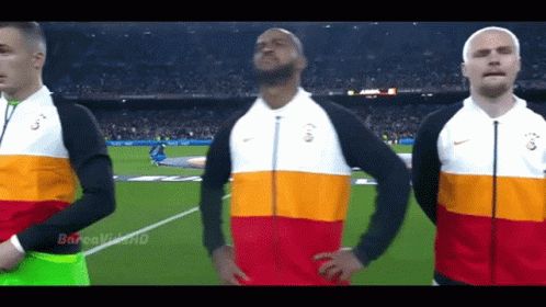 Three Men Stand On A Soccer Field Wearing Nike Jackets With The Letters G On Them GIF