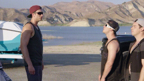 Three Men Standing Next To Each Other On A Beach Near A Lake . GIF