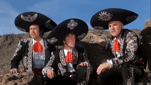 Three Men Wearing Mariachi Outfits And Sombrero Hats Are Sitting On A Rock GIF