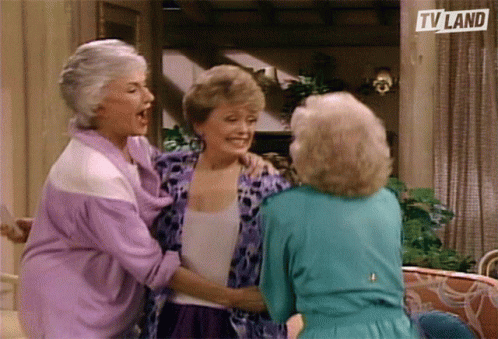 Three Older Women Are Hugging Each Other In Front Of A Tv Land Sign GIF
