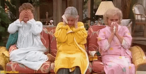 Three Older Women Are Sitting On A Couch Covering Their Eyes With Their Hands And Blowing Their Noses . GIF