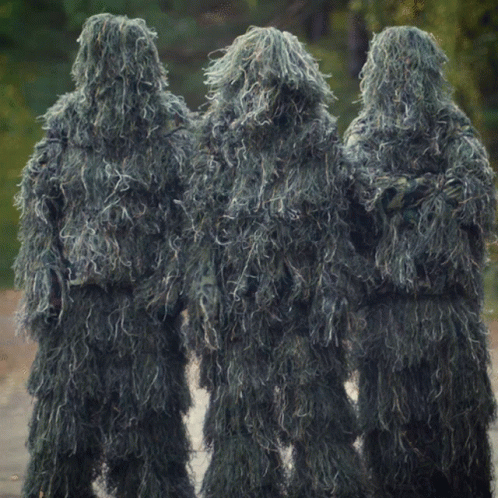 Three People Dressed In Sniper Suits Are Standing In A Line GIF