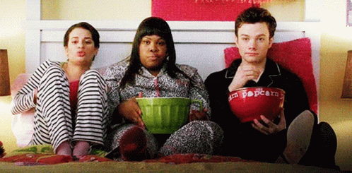 Three People Sitting on Bed with Popcorn