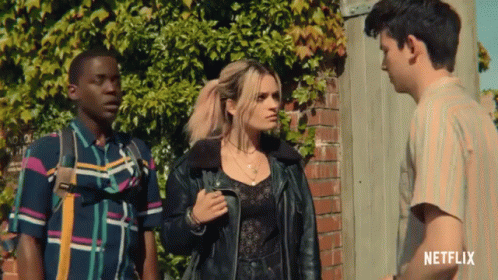 Three People Standing In Front Of A Brick Wall With A Netflix Logo On The Bottom Right GIF