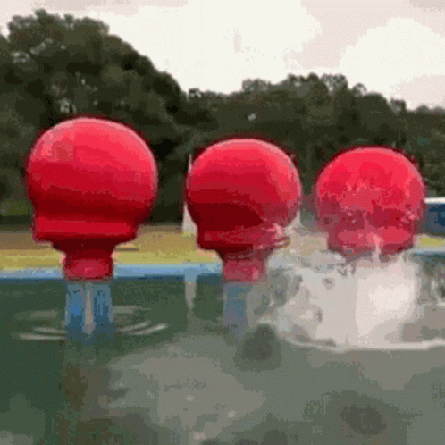 Three Red Balls Are Floating In A Pool . GIF