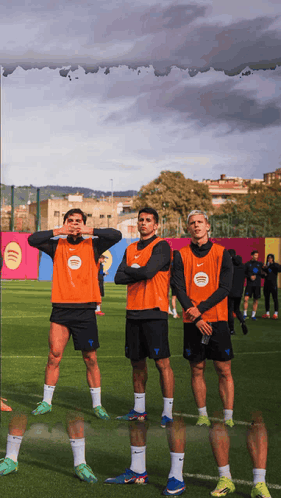 Three Soccer Players Wearing Orange Vests With Spotify Written On Them GIF
