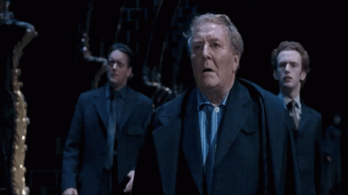 Three Suited Men in Dark Room, One Surprised