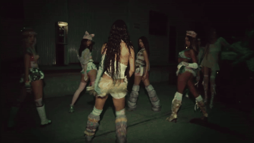 Three Women Are Dancing In A Dark Room With One Wearing A Pink Cat Hat GIF