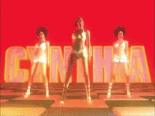 three women are dancing in front of a sign that says cantha